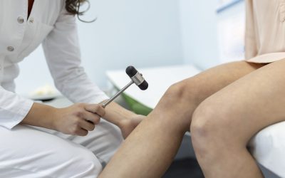 Doctor neurologist knocking on knee of patient with hammer in clinic closeup. Diagnosis of neurological pathology of knee reflex concept