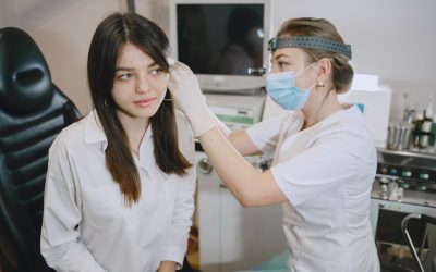 Woman patient in the medical office. Doctor in medical mask. Lor checks the woman' ears.